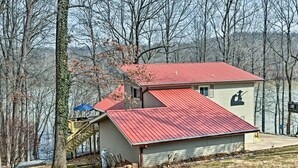 Une cabane avec un toit rouge, une terrasse en bois et un escalier menant à une zone abritée.