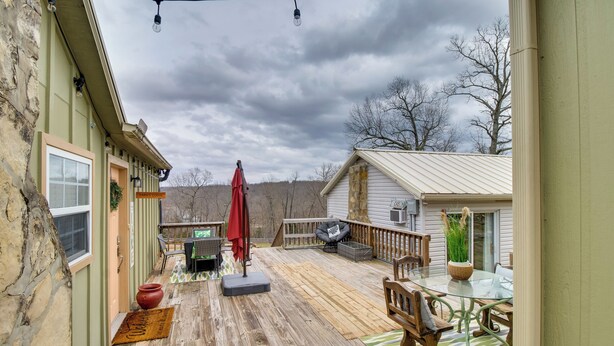 Una terraza de madera con mobiliario exterior, una sombrilla roja y una mesa de vidrio.