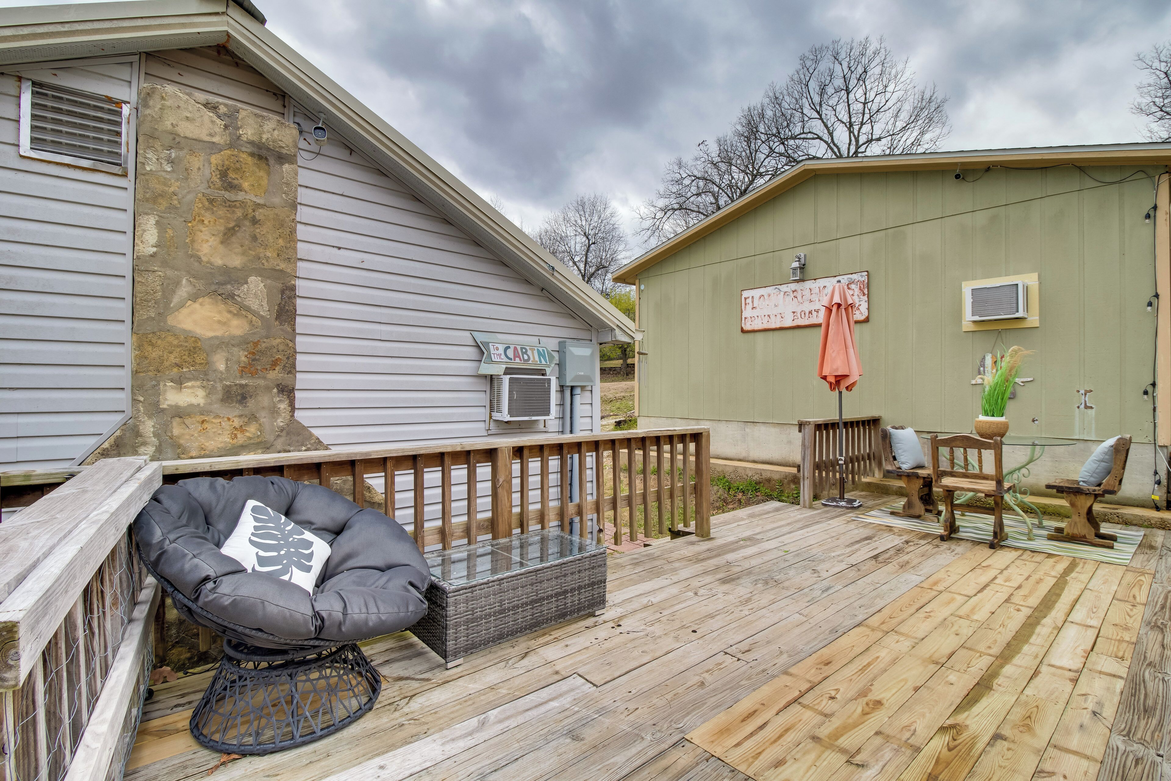 A wooden deck with a stone wall, a covered seating area, and a small shed.