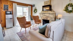 Una sala acogedora con chimenea de piedra, dos sillones de cuero, un sofá, un televisor y un microondas.