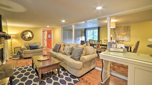 A living room with a sofa, coffee table, and a glass-top table with a sign. - 'pelican Bay Retreat' on Lake Barkley w/ Kayaks! (Cadiz)