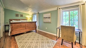 A bedroom with a wooden bed, a desk, a chair, a patterned rug, and a window with curtains. - 'pelican Bay Retreat' on Lake Barkley w/ Kayaks! (Cadiz)