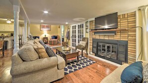 A living room with a fireplace, a television mounted above it, and a dining area in the background. - 'pelican Bay Retreat' on Lake Barkley w/ Kayaks! (Cadiz)