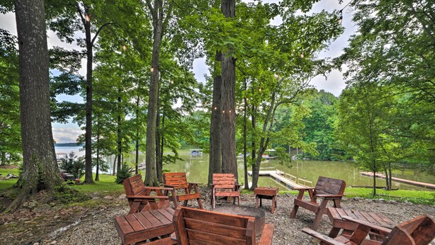 A serene outdoor seating area with wooden benches and tables, surrounded by trees and overlooking a lake. - 'pelican Bay Retreat' on Lake Barkley w/ Kayaks! (Cadiz)