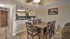 A modern kitchen with a central island, wooden chairs, and a dining table. - Scottsdale Condo w/ Pool Access: Hike, Swim & Shop (Scottsdale)