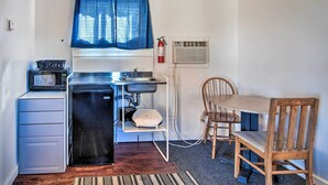 A compact kitchenette with a microwave, sink, and small refrigerator. There is a dining table with chairs and a blue curtain over the window. - Vacation Rental in Loveland 1 Mi to Downtown! (Loveland)