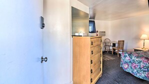 A compact room with a bed, a wooden dresser, a desk with a chair, and a small table with a lamp. - Vacation Rental in Loveland 1 Mi to Downtown! (Loveland)