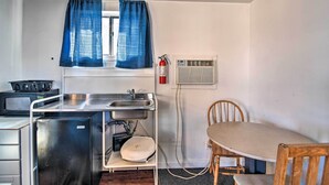 A compact kitchenette with a stove, sink, and refrigerator. A fire extinguisher is mounted on the wall. - Vacation Rental in Loveland 1 Mi to Downtown! (Loveland)