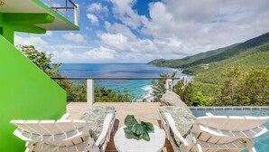 Una terraza con vistas al océano, mobiliario exterior y una piscina.
