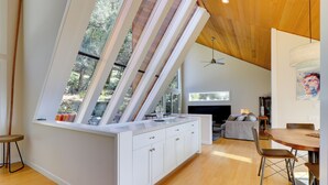 A modern kitchen with white cabinetry, a wooden ceiling, and large windows offering a view of the outdoors. - Luxe Santa Rosa Home ~ 3 Mi to Downtown! (Santa Rosa)