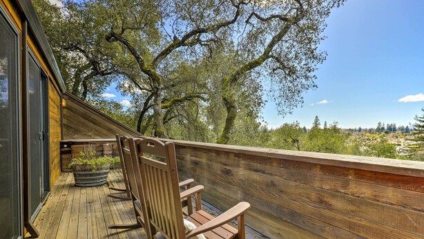 A wooden deck with rocking chairs and a view of trees and landscape. - Luxe Santa Rosa Home ~ 3 Mi to Downtown! (Santa Rosa)