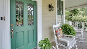 A green door with a window, a white porch with rocking chairs, and a small plant by the door. - Historic Hot Springs Home < 1 Mi to Oaklawn! (Hot Springs)
