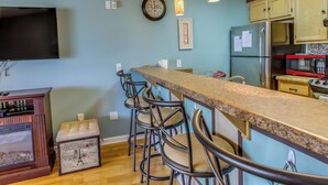Une cuisine avec un coin bar, une horloge et un réfrigérateur.