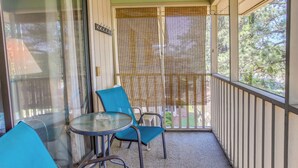 Un balcon avec une porte vitrée, deux chaises bleues et une petite table ronde.
