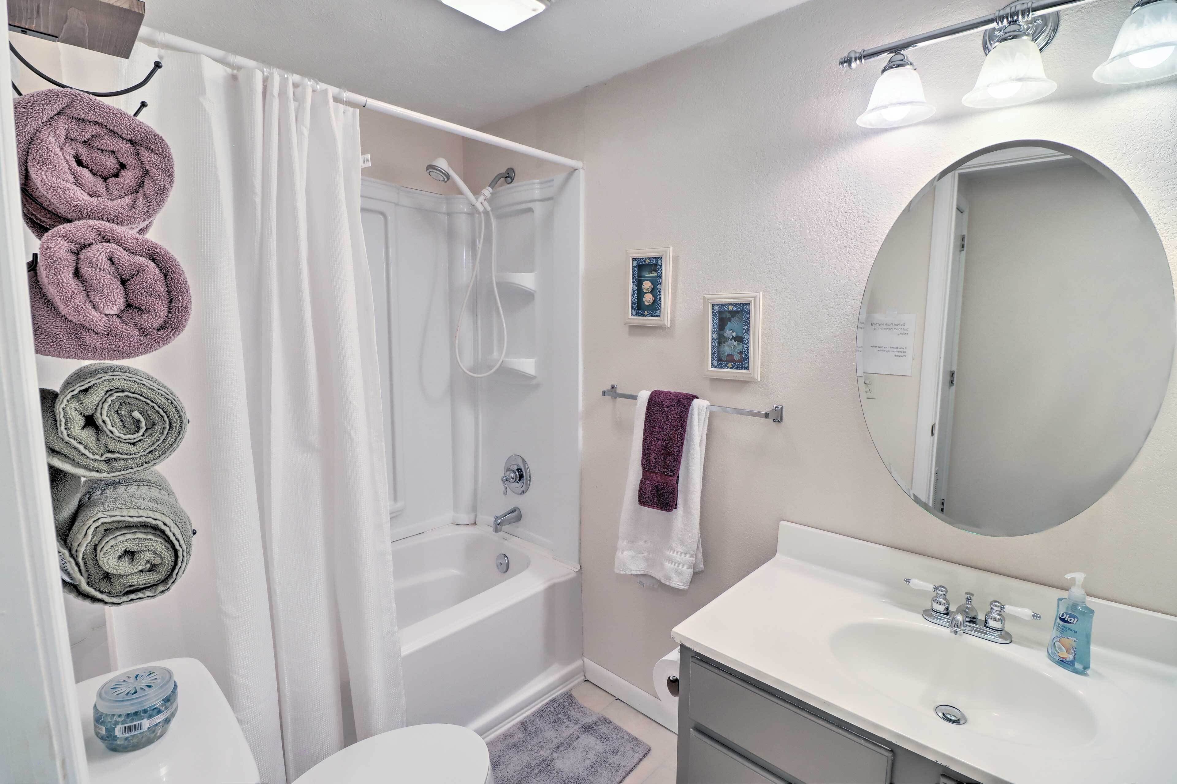 Une salle de bain équipée d’une baignoire, d’un lavabo, de toilettes et de serviettes suspendues sur un porte-serviettes.