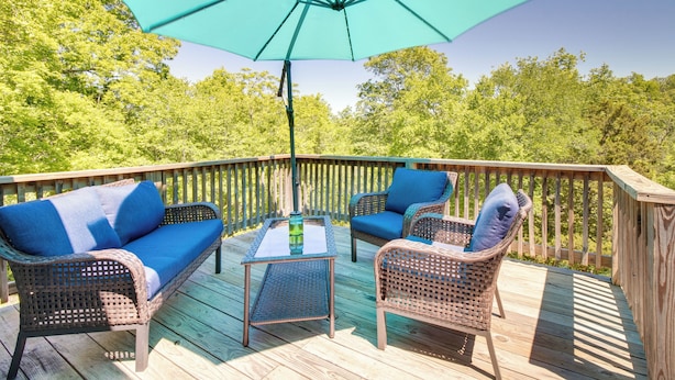 A wooden deck with wicker furniture, including a sofa and chairs, and a table with a glass top. - Fisherman-friendly Bull Shoals Escape on Lakefront (Bull Shoals)