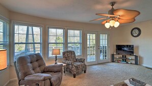 A living room with a ceiling fan, a TV, and a fireplace. - Fisherman-friendly Bull Shoals Escape on Lakefront (Bull Shoals)