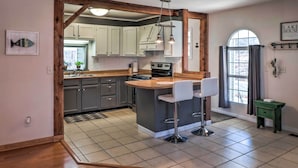 A kitchen with a bar area, wooden beams, and a view of the outdoors. - Fisherman-friendly Bull Shoals Escape on Lakefront (Bull Shoals)