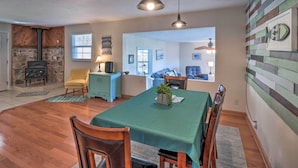 A dining area with a wooden table, chairs, and a green tablecloth. There is a stone fireplace and a blue cabinet in the background. - Fisherman-friendly Bull Shoals Escape on Lakefront (Bull Shoals)