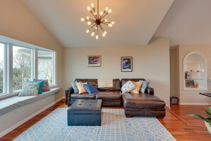 A living room with a brown leather sofa, a blue ottoman, a patterned rug, and a star-shaped ceiling light. - Washington Vacation Rental w/ Hot Tub Near Tacoma (University Place)