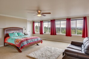 A bedroom with a bed, a ceiling fan, a window with curtains, and a view of trees. - Washington Vacation Rental w/ Hot Tub Near Tacoma (University Place)