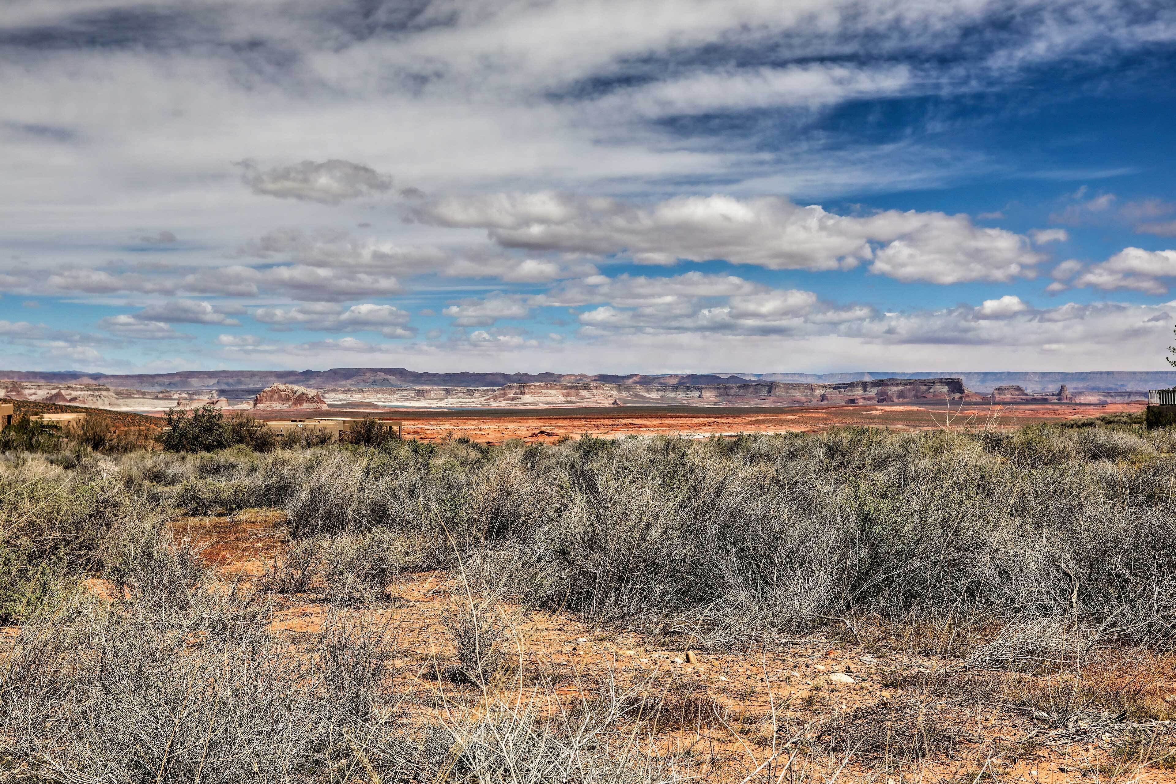 Un vaste paysage ouvert, avec une végétation clairsemée et des collines lointaines sous un ciel partiellement nuageux.