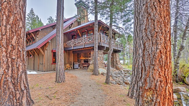 A rustic cabin with a wooden exterior, a balcony, and a stone foundation.