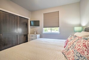 A bedroom with a large bed, a dresser, a TV mounted on the wall, and a window with blinds. - Lake Chelan Condo, Walk to Brewery & Wineries (Manson)
