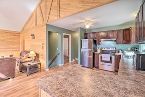 A spacious living area with a wooden ceiling, a kitchen with dark wooden cabinets, a stainless steel refrigerator, and an oven. - Hike & Swim: Family Home in Albrightsville! (Albrightsville)