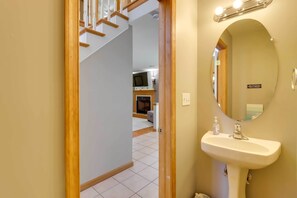 A bathroom with a sink, mirror, and a small bottle of hand sanitizer.