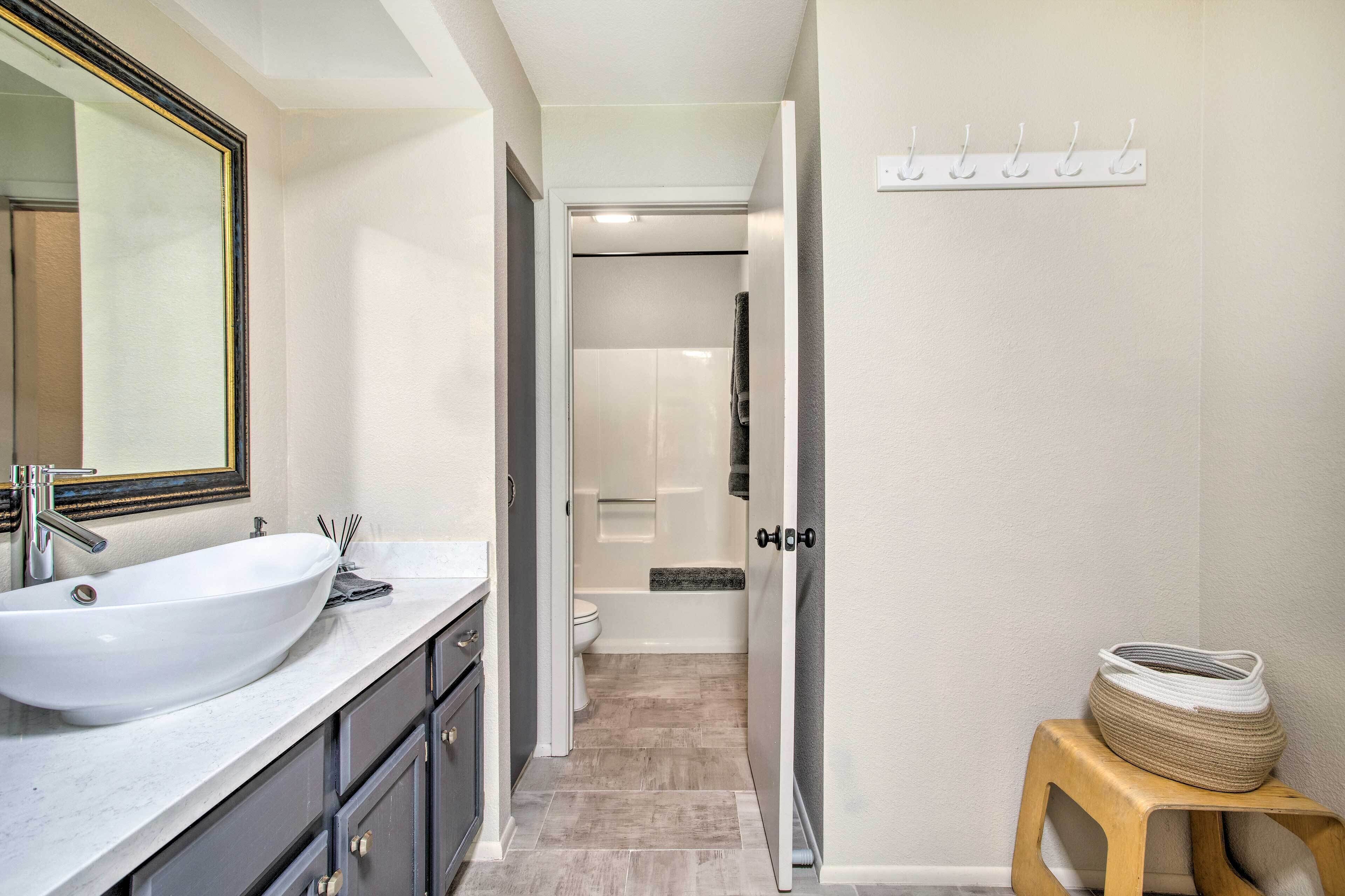 A modern bathroom with a large white sink, a mirror, and a shower area.