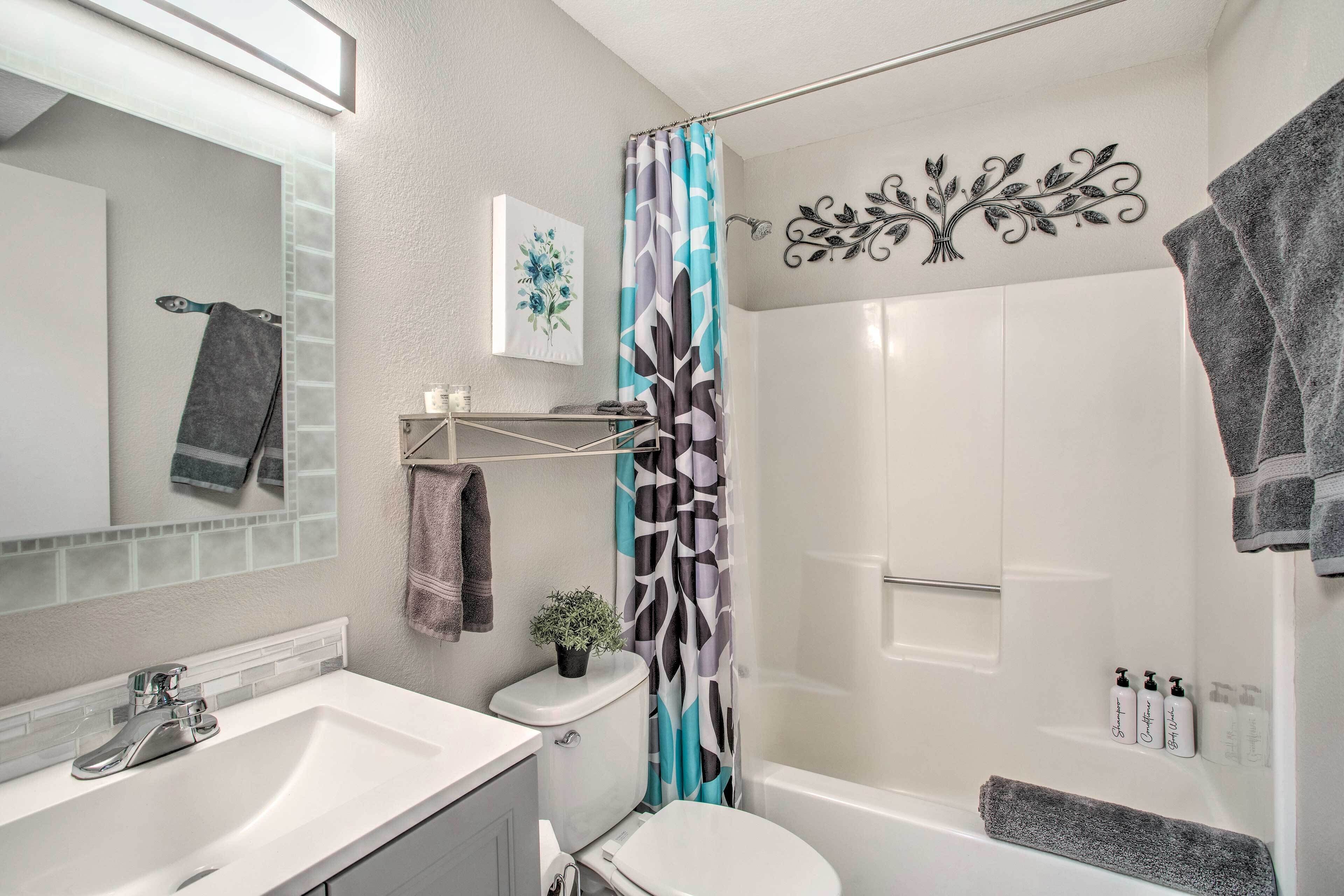 A modern bathroom with a shower, toilet, sink, and a mirror.