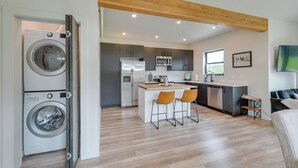 Une cuisine moderne dotée d’un îlot central, d’appareils électroménagers intégrés et d’un plafond en bois.