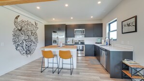 Une cuisine moderne avec des meubles de couleur sombre, un îlot central et un coin repas équipé de deux chaises.