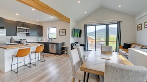 Une cuisine moderne dotée d’un îlot central, de tabourets de bar et d’un coin repas avec une grande table et des chaises.