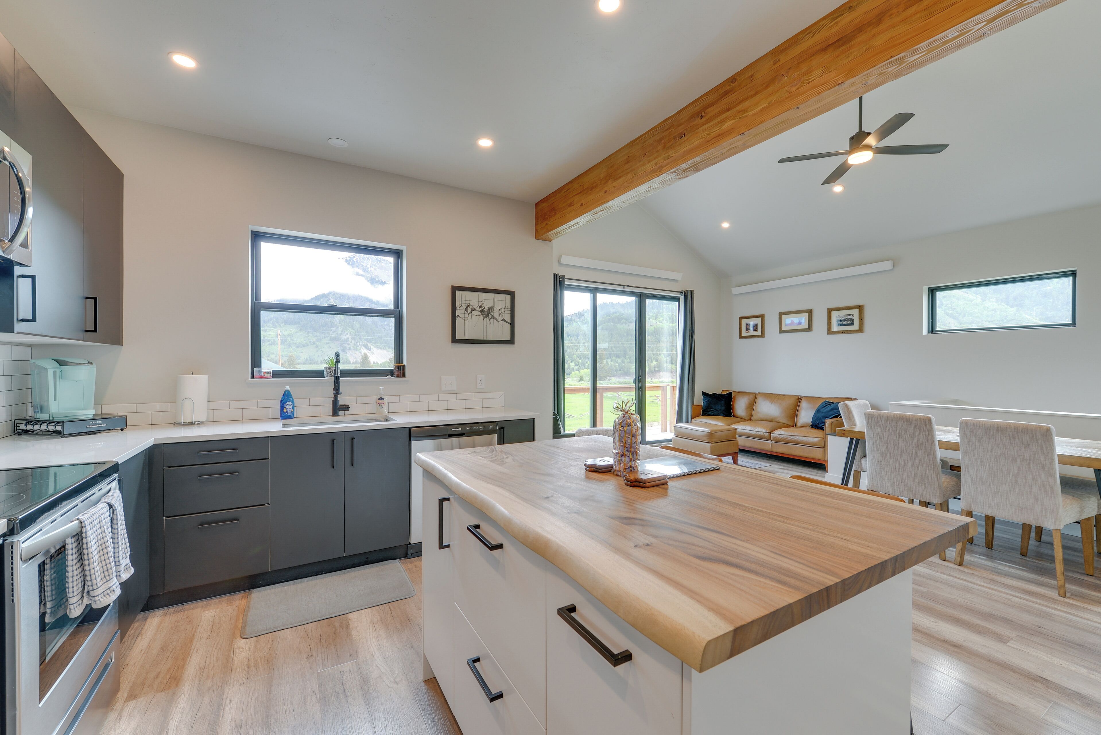Une cuisine moderne dotée d’un îlot central en bois, d’appareils électroménagers intégrés et de grandes fenêtres.