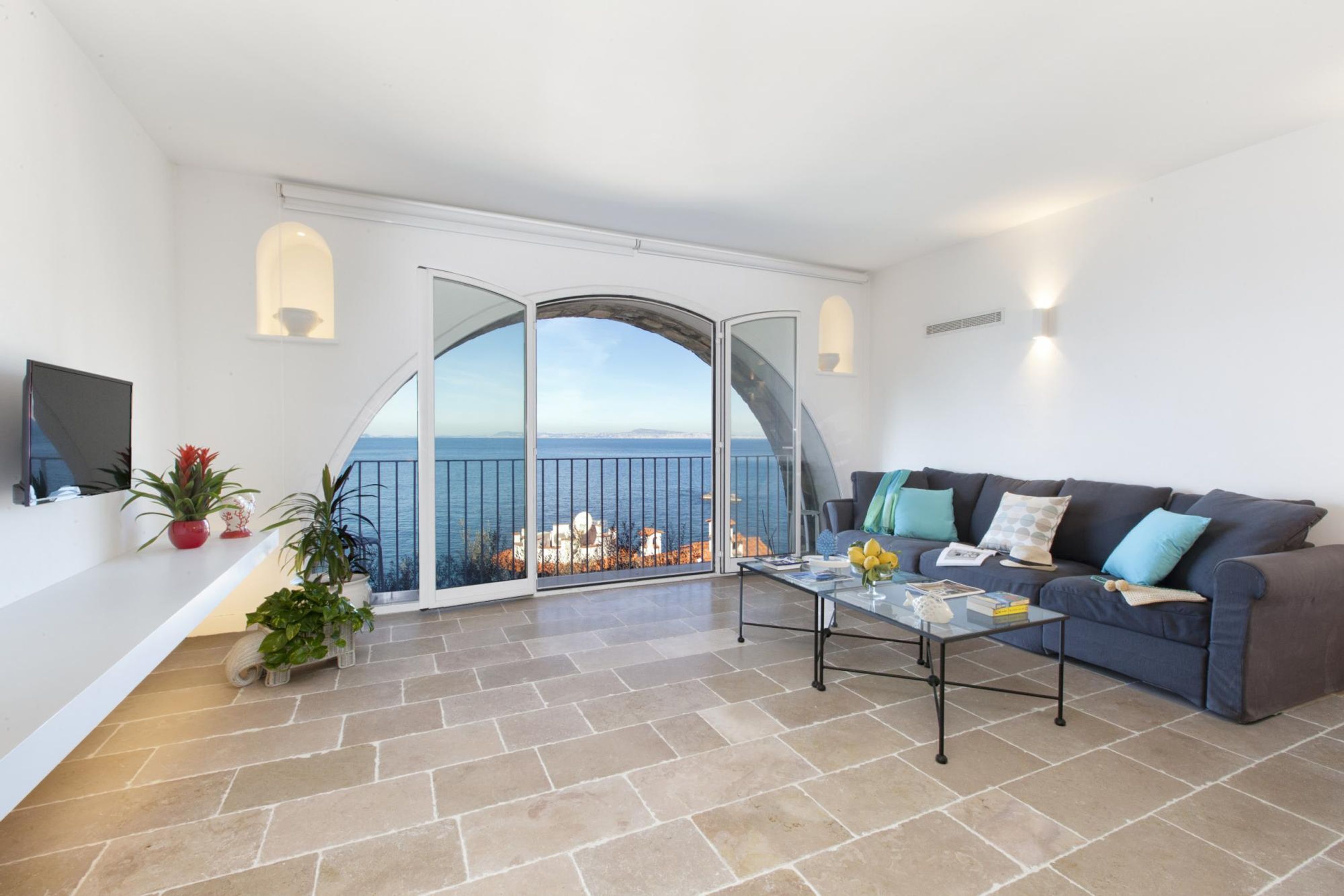 A spacious living room with a large window offering a sea view, a comfortable sofa, and a coffee table.