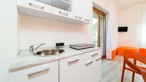 Una cocina moderna con armarios blancos, un lavamanos de acero inoxidable y una encimera con una cafetera y un tostador.