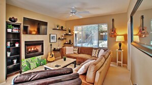 A cozy living room with a fireplace, a sofa, a coffee table, and a bookshelf. - Near Bellair Golf Club! Phoenix Abode w/ Pool (Phoenix)