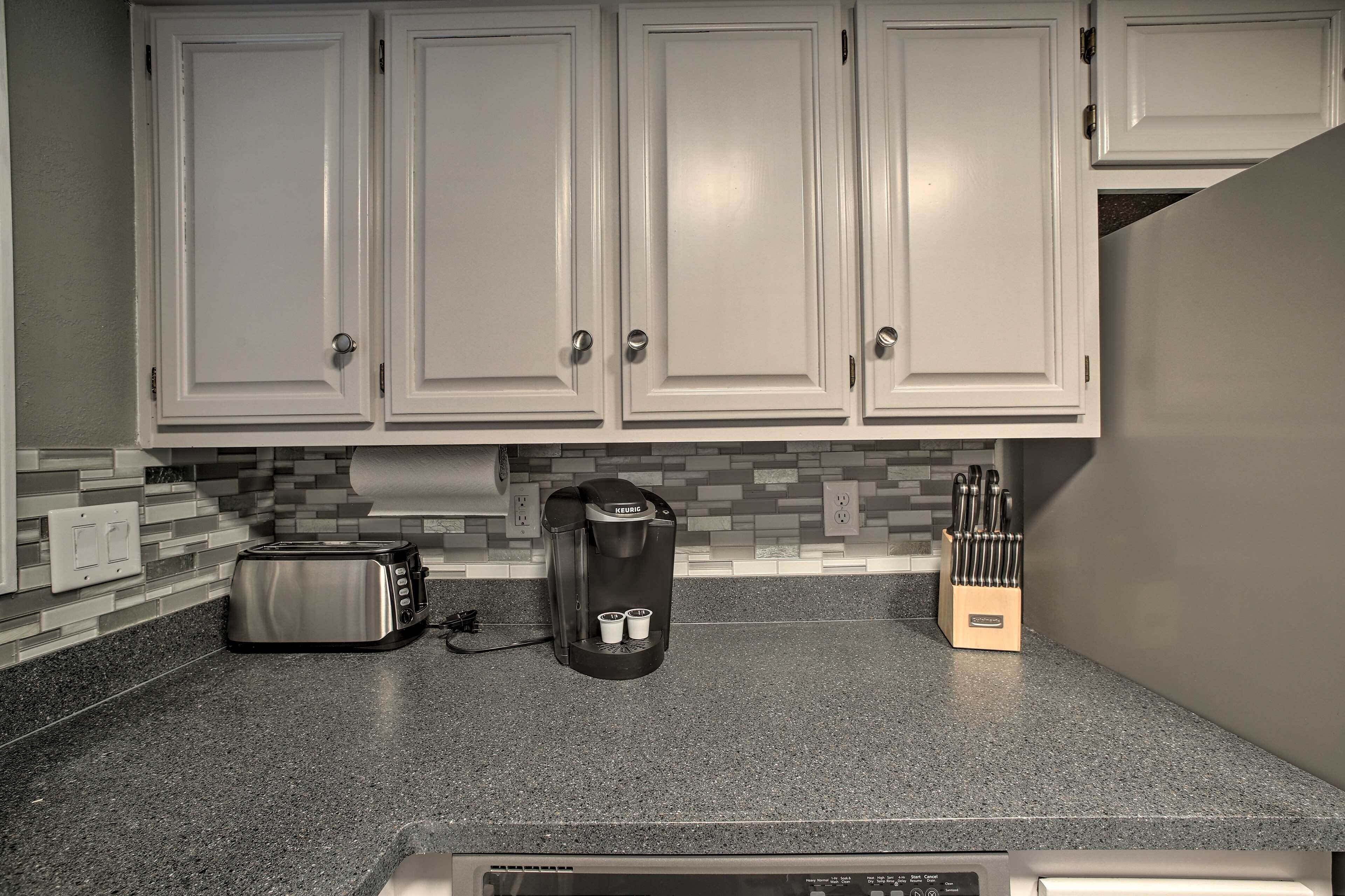 A kitchen with white cabinets, a toaster, a coffee maker, and a knife block.