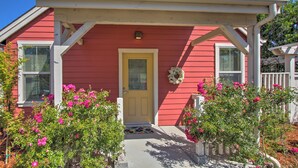 A red house with a yellow door, white porch, and pink flowers. - Serene Bungalow-style Home in Point Reyes Station! (Point Reyes Station)