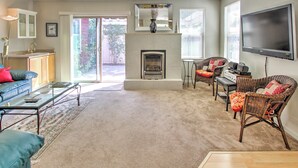 A living room with a fireplace, a television, wicker furniture, and a glass coffee table. - Serene Bungalow-style Home in Point Reyes Station! (Point Reyes Station)