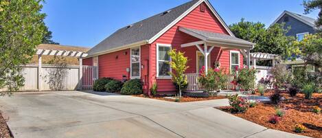A red house with a covered porch and a well-maintained front yard.