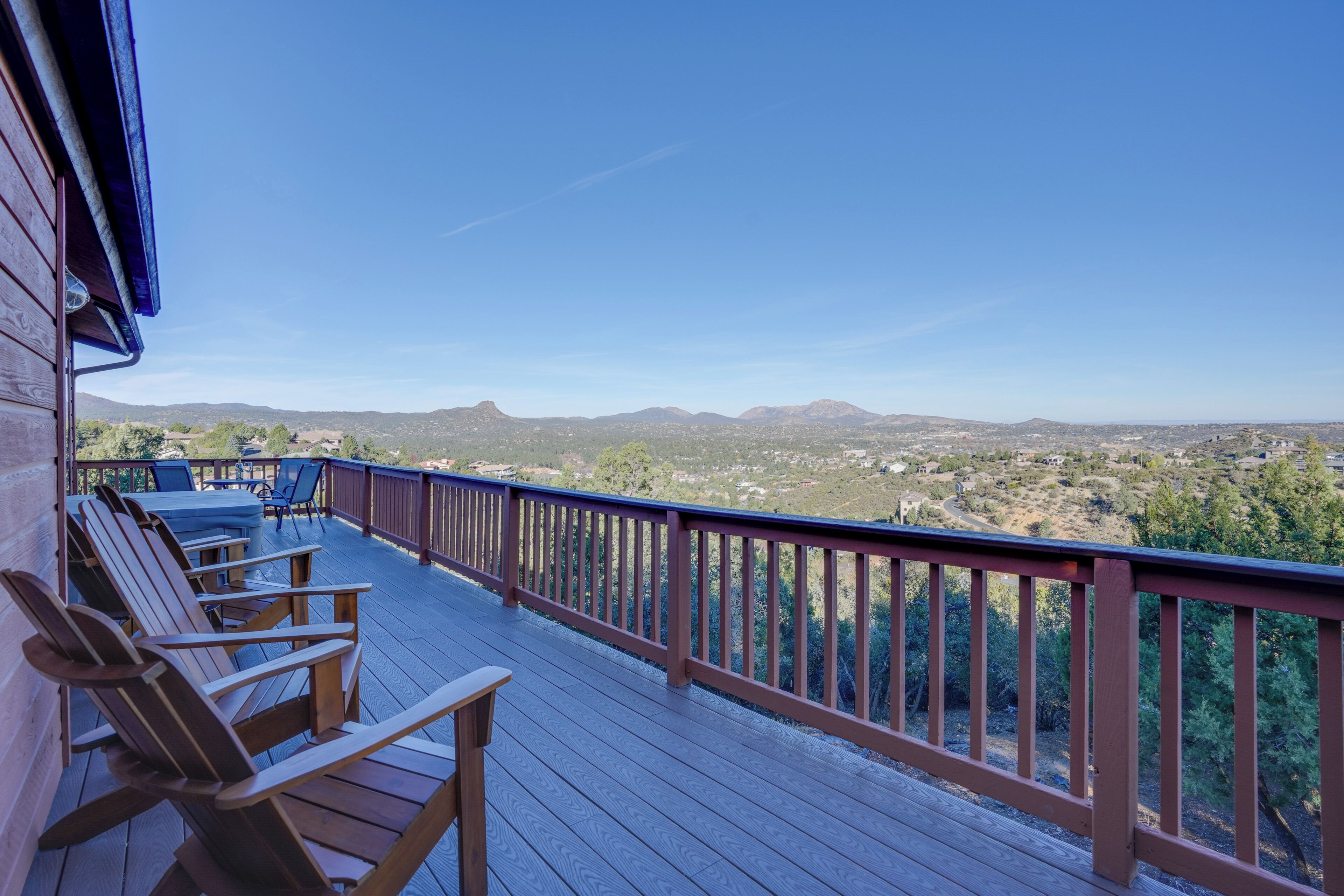 A wooden deck with chairs and a table, overlooking a mountainous landscape.