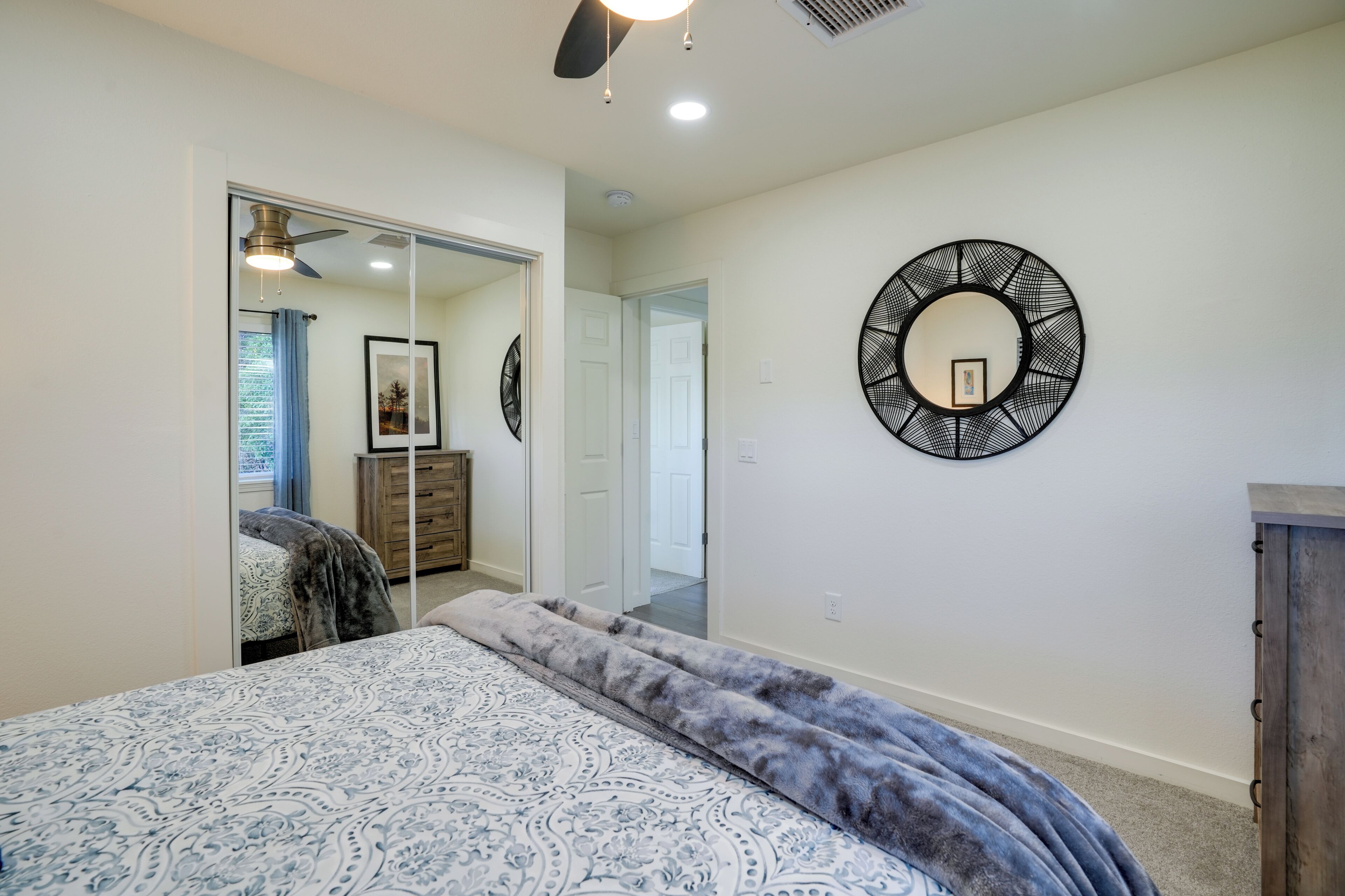 A bedroom with a bed, a large mirror, and a ceiling fan.