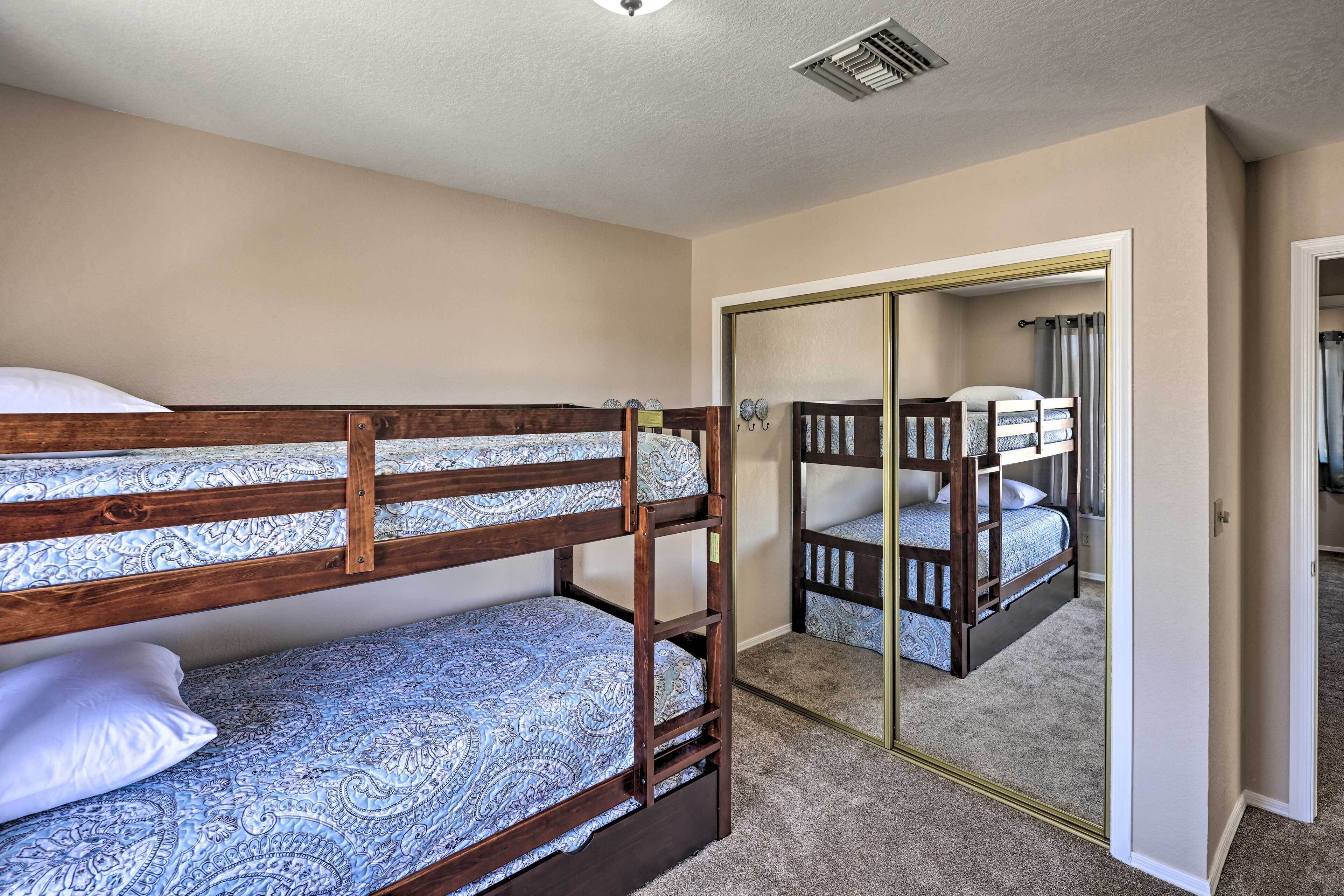 A bunk bed room with a mirror and a door leading to another room.