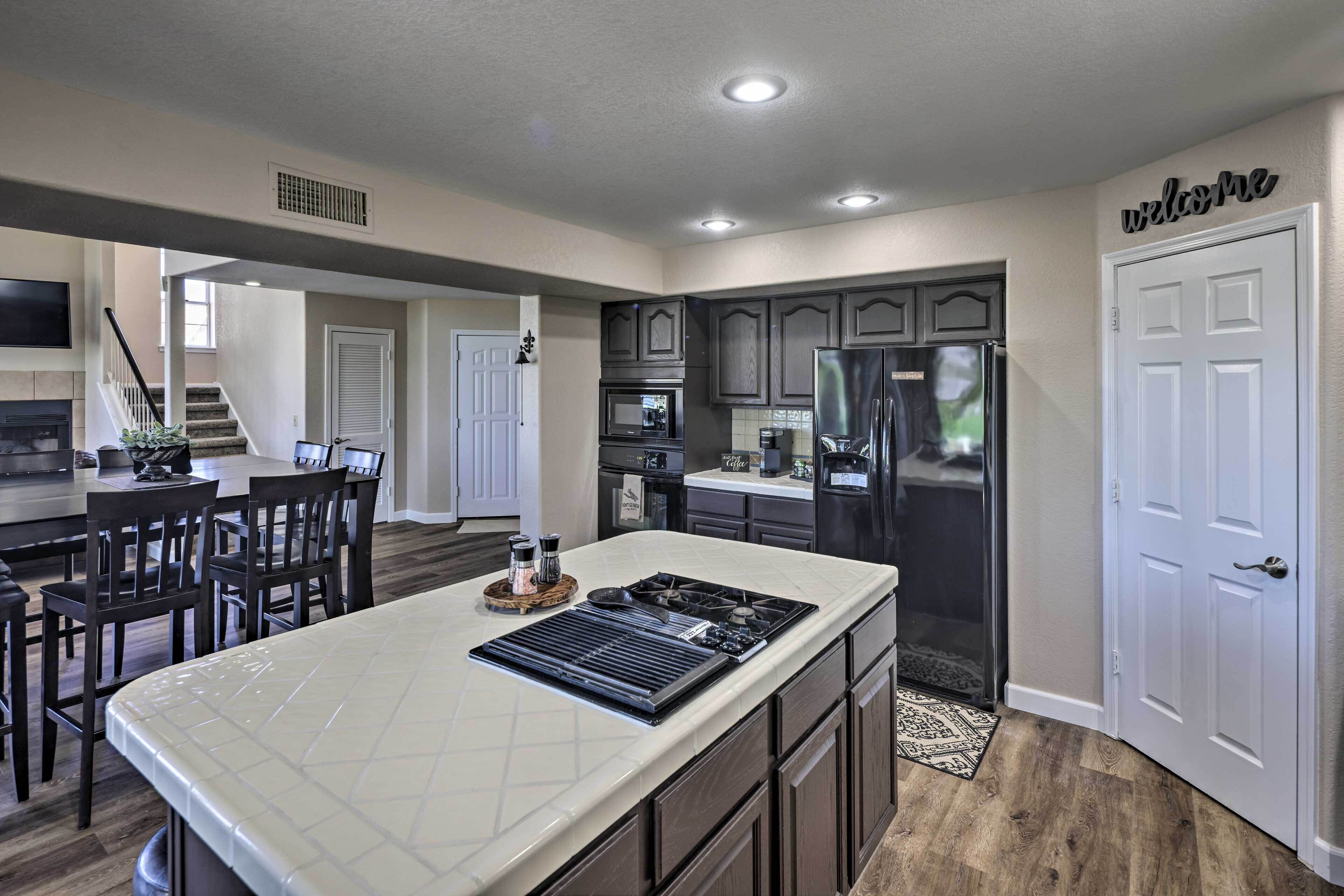 A modern kitchen with dark cabinetry, a large island, and a built-in oven.