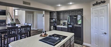 A modern kitchen with dark cabinetry, a large island, and a built-in oven.