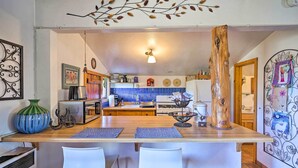 A kitchen with a wooden island, white bar stools, and a decorative tree trunk. - Cozy 'story Book Barn Cottage' w/ Scenic View (Julian)