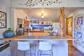 A kitchen with a wooden island, white bar stools, and a decorative tree trunk. - Cozy 'story Book Barn Cottage' w/ Scenic View (Julian)